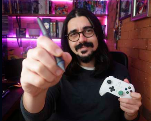 Andy Silveira segurando uma caneta e um controle de videogame